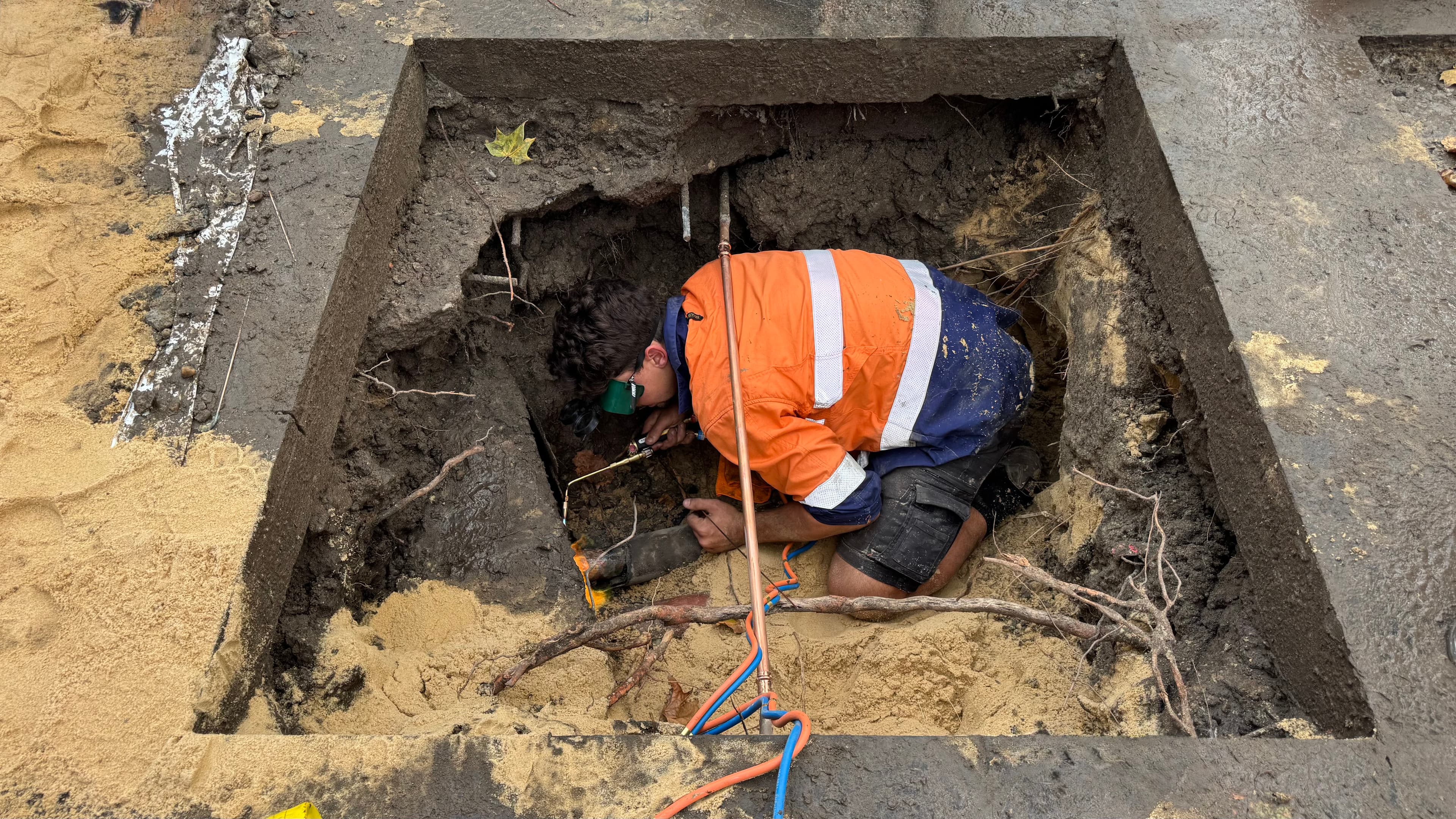 Excavation pit exposing the damaged water main prior to repair.